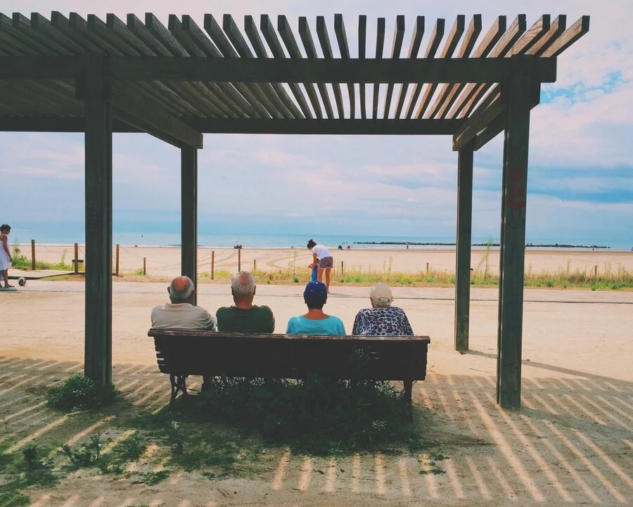 Peoples siting under louvered metal pergola enjoying beach view